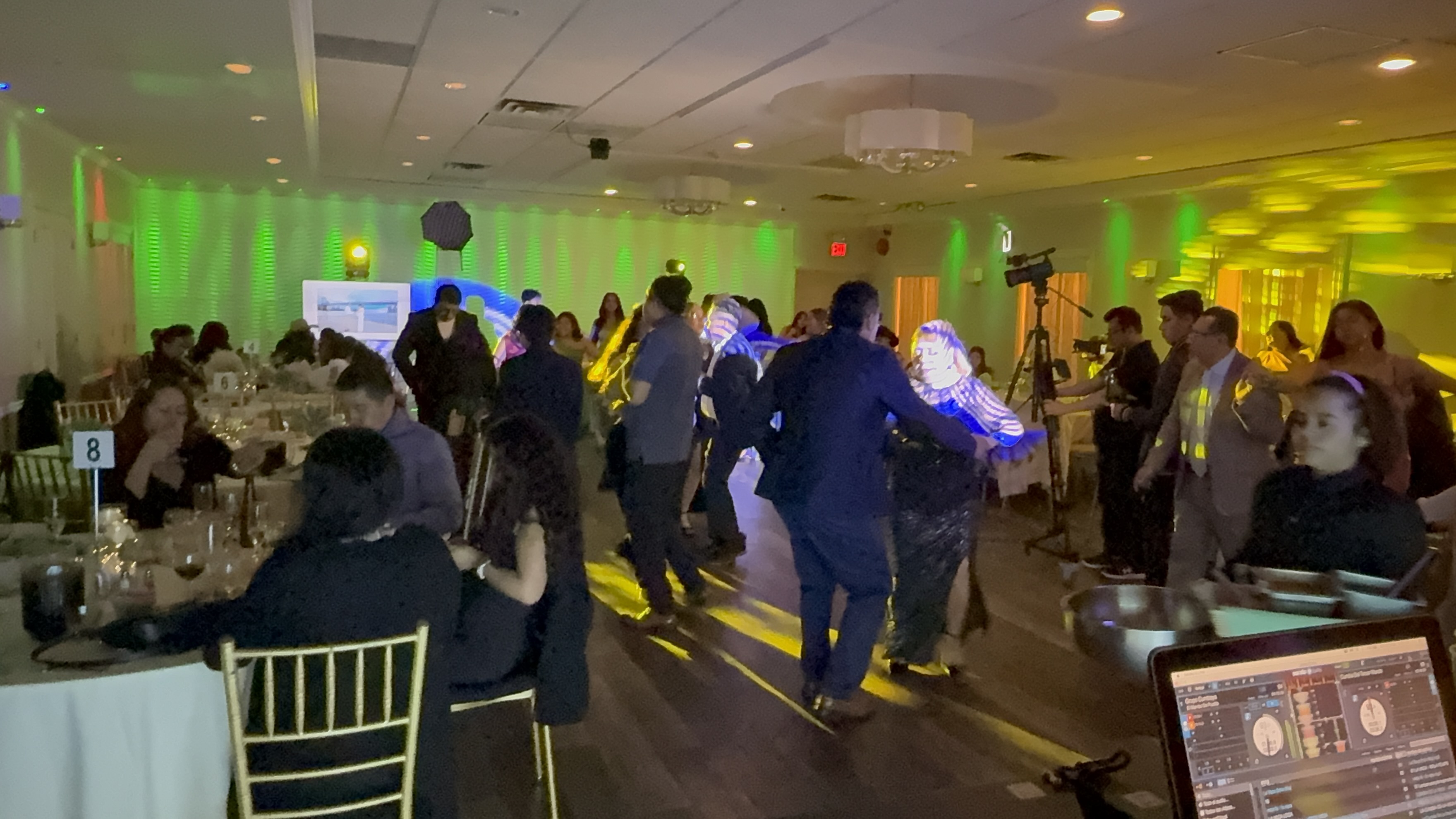Fiesta elegante con luces verdes y amarillas, invitados bailando en el salón