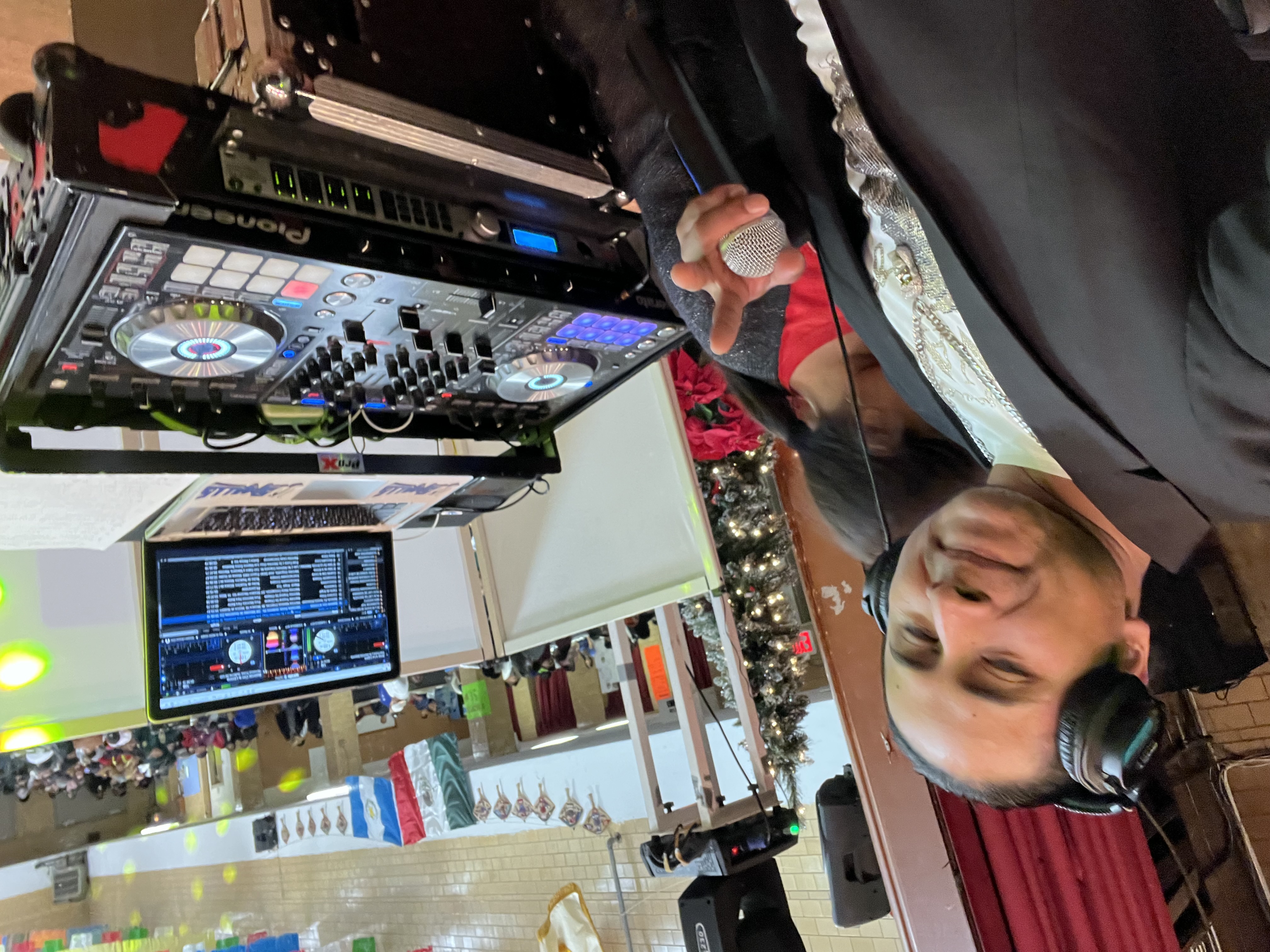 DJ Smalls en acción con micrófono y controlador Pioneer en evento navideño